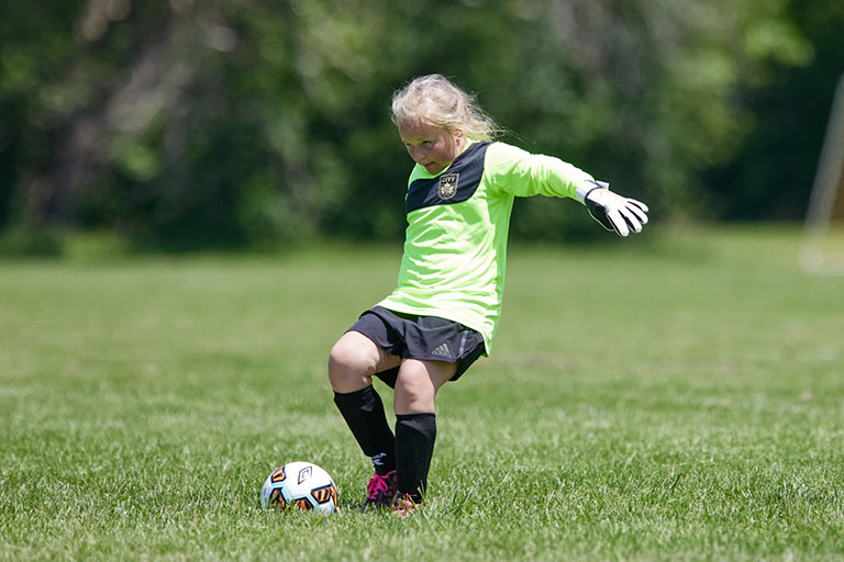 Young boy winding up to kick the ball.